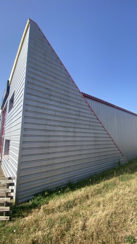 Pignon d'un bâtiment en bardage métallique gris, terni avant nettoyage