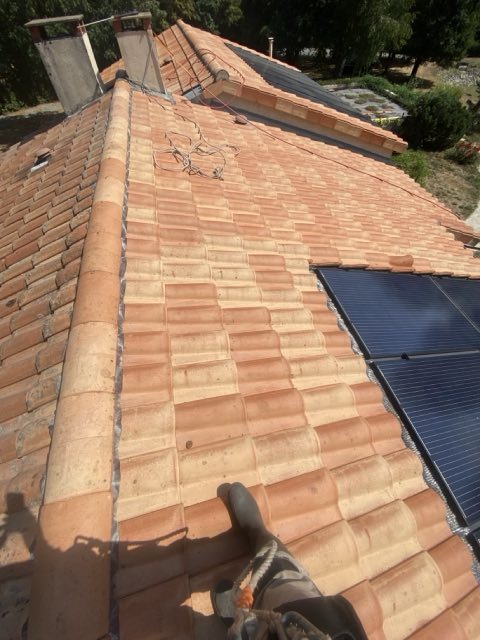 Versant de toiture en tuiles romanes après nettoyage, à côté de panneaux solaires
