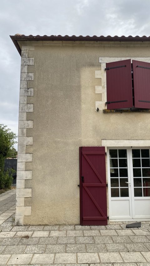 Angle de façade enduite avec chaîne d'angle en pierre, grisé avant nettoyage