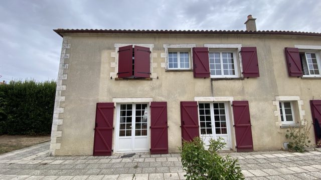Façade enduite d'une maison aux volets rouges, grisée et tachée avant nettoyage